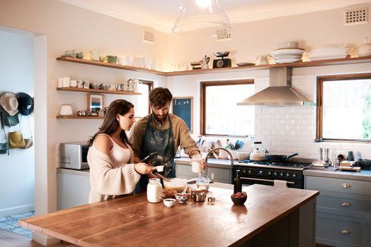 Bake your home a happy place. a young couple using a digital tablet while preparing breakfast at home.