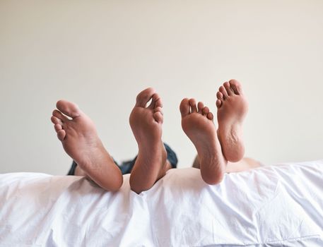 Today was made for resting. an unrecognizable couples bare feet on the edge of the bed at home.