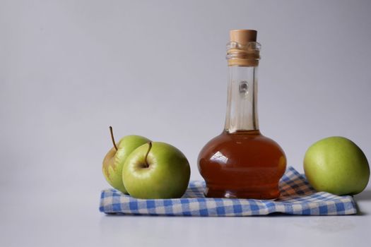 apple vinegar in glass bottle with fresh green apple on table