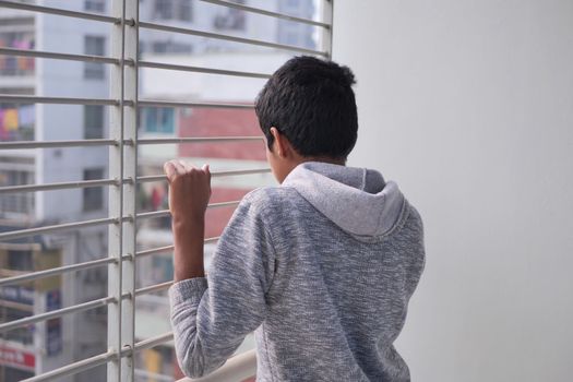sad teenage boy looking through window