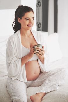 Great joy is on the way. a pregnant woman relaxing with a beverage at home.
