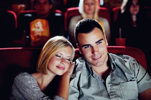 Hes her Prince Charming. A happy young woman cuddles up close to her boyfriend on their date at the movies.