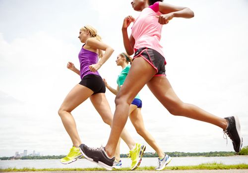 Ladies keeping fit. Cropped side view of a group of athletes jogging beside a lake.