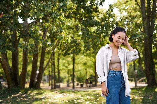 Image of korean girl walking in park, smiling while having a mindful walk in woods