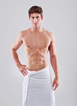 Looking good and feeling great. Studio shot of a handsome bare chested young man with his waist wrapped in a towel.