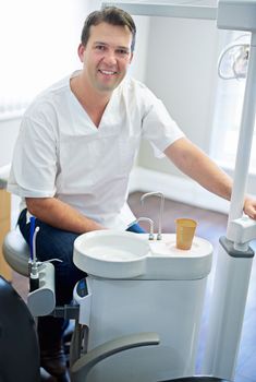 I hope youve been brushing. Portrait of a male dentist sitting by the dental equipment in his office