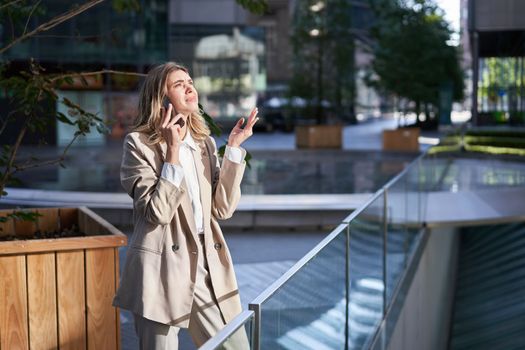Frustrated corporate woman standing on street and having a difficult phone call, hear bad news on telephone conversation