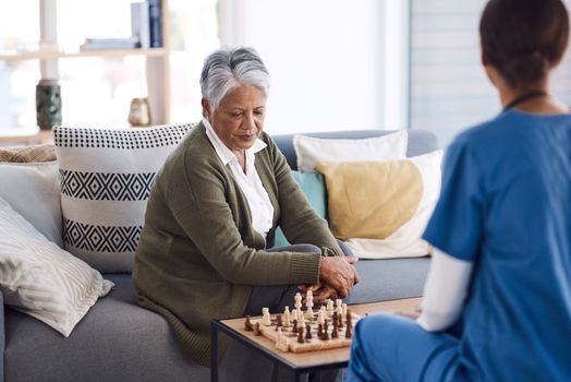 I need to think carefully about my next move...a senior woman playing chess with a young nurse in a retirement home.