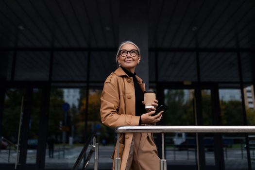 stylish businesswoman with cup of coffee outside