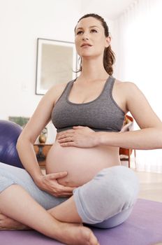 Her baby is in safe hands. a young pregnant woman exercising at home.