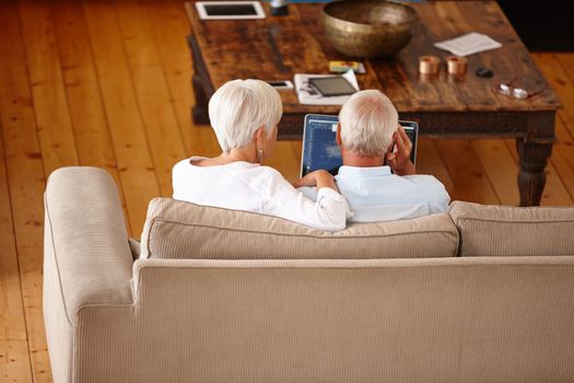 Making an informed decision together. Rearview shot of a senior couple using a digital tablet at home.