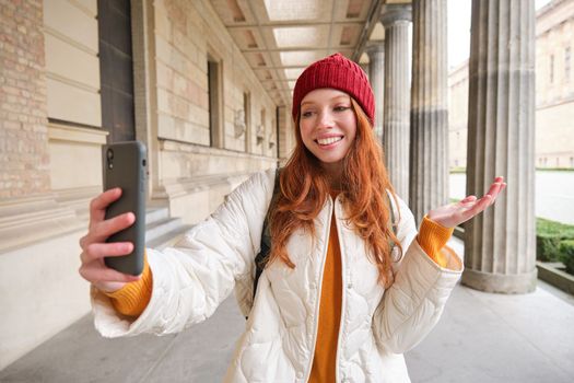 Happy girl tourist demonstrates something on video chat smartphone, shows sightseeing attraction to friend while on mobile phone app call