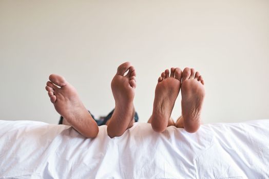 Perfect day to rest. an unrecognizable couples bare feet on the edge of the bed at home.