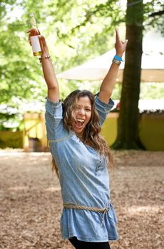 Party girl. a young woman shouting in excitement with her arms raised at a festival.