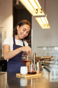 Cute korean barista girl, pouring coffee, prepare filter batch brew pour over, working in cafe