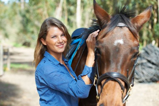 Horse riding is my first love. Portrait of a happy woman standing outside and rubbing her horse.