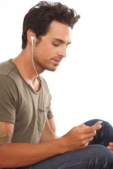 Finding the best track. A handsome young man listening to music on his mp3 player isolated on white.