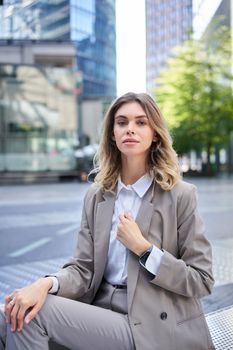 Vertical portrait of confident businesswoman in suit, adjust her blazer, looks self-assured. Candidate waits for an interview