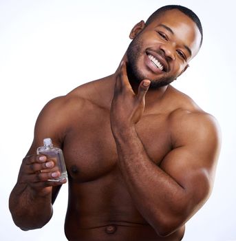 When you smell good, you feel good. Studio portrait of a handsome young man applying cologne against a white background.