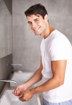 Good hygiene keeps him healthy. Portrait of a young man washing his hands.