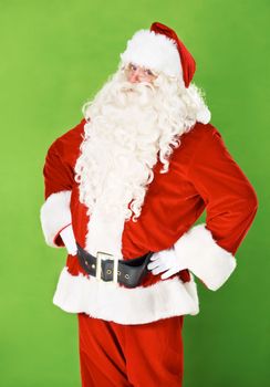 No nonsense now. Santa Claus standing with his hands on his hips againts a green background.