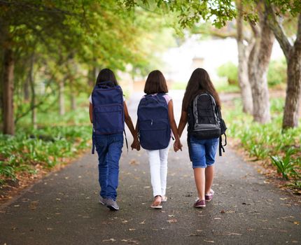 Friends forever. Three young female classmates walking outside.