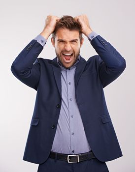 Really. Studio shot of a businessman holding his head and shouting in anger.