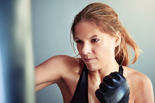 Shes a fierce fighter. a female boxer training with a punching bag.