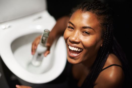 Black woman, face and drinking alcohol by toilet in party event, birthday celebration or nightclub social gathering. Portrait, smile or happy drunk person with beer bottle in music festival bathroom