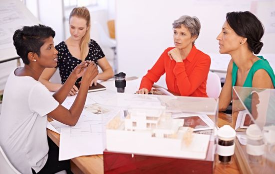 Bringing her expertise to the table. A group of female architects working together on a project at a conference table.