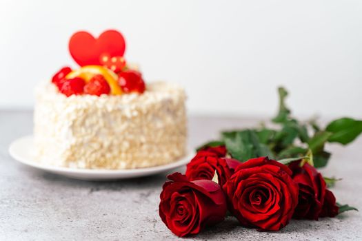 Roses flowers and Valentine's Day cake with heart shape and fruits, strawberries. Birthday Cake for celebration. Valentine's Day and love concept. Present with love