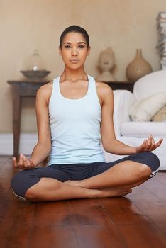 Meditation- my wellness secret. Full length shot of a young woman doing yoga at home.