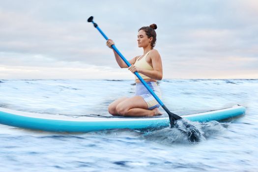 Woman, fitness and paddle board in sea for fitness, training and workout outdoor in nature with paddle. Sport athlete, healthy and exercise in ocean water for health, wellness and cardio practice