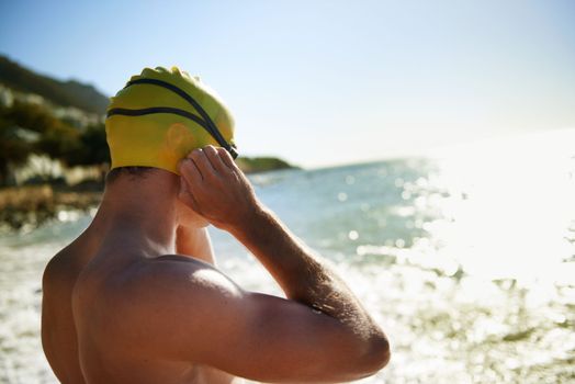 Getting ready for a swim. A young man putting on his goggles for a swim in the ocean.