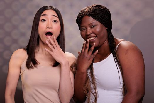 Two diverse women laughing with hand over mouth