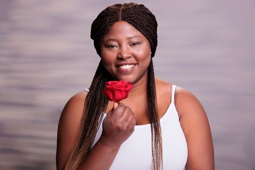 Beautiful body positive woman giving red rose bud portrait