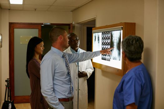 Healing is their calling. a team of surgeons discussing a patients medical scans.