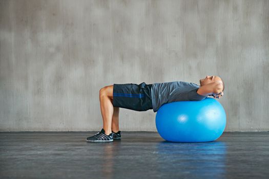 Strength and determination. an athletic young man lying on an exercise ball.