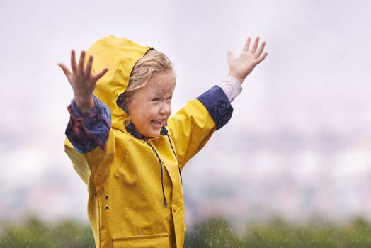 To enjoy the rainbow, first enjoy the rain. an adorable little girl playing outside in the rain.