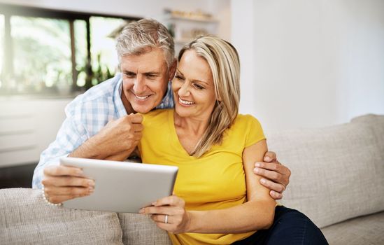 Looking for fun things do add to our bucket list. a mature couple using a digital tablet while relaxing at home.