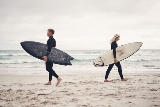 You might find your soulmate while out surfing. two people walking on the beach with their surfboards.