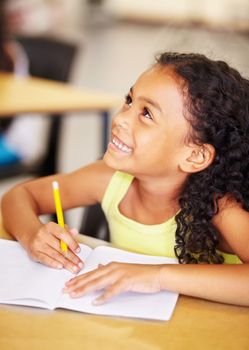 She loves learning. A cute little girl smiling as she does her homework in class.