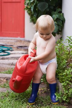 Curious about how nature works. An adorable baby boy watering the garden.