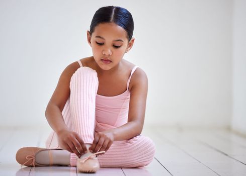 Getting ready to dance the day. a little girl putting on her shoes in a ballet studio.
