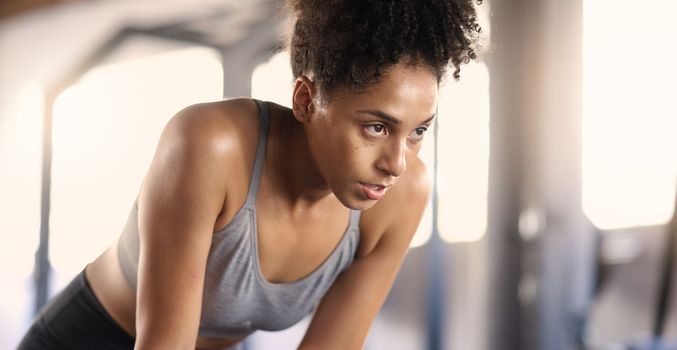Gym, training and tired black woman breathing after exercise, workout and sports fitness. Woman in a health and wellness club breathe and relax after intense athlete challenge with focus