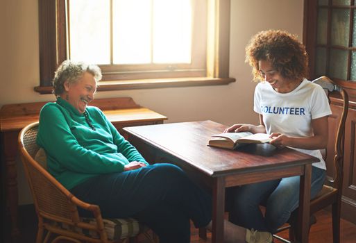Bringing happiness through reading. a volunteer reading to a senior woman at a retirement home.