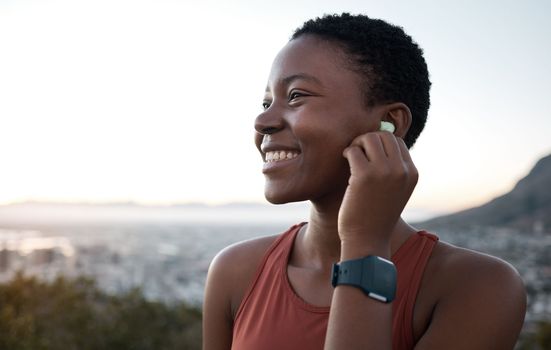 Earphones, music and fitness with a sports black woman in nature for exercise or a cardio workout. Training, thinking and running with a female athlete streaming audio while endurance exercising
