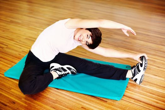 Woman stretching. Portrait of smiling woman doing a stretching exercise in gym.