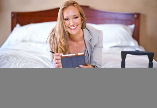 The only suite I book for business. A young businesswoman using a digital tablet in her hotel room.