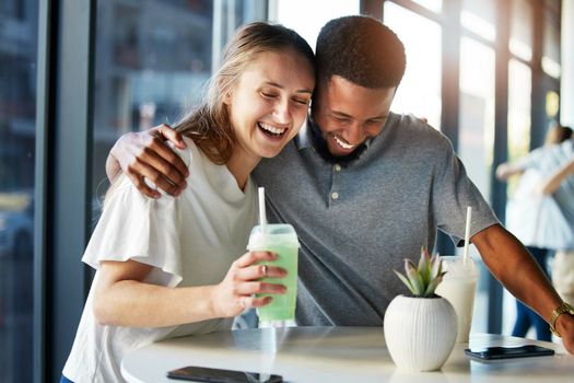 Dating, restaurant and couple with smoothie drink hugging, having fun and laughing together on romantic date. Love, relationship and interracial couple enjoying milkshake, cocktail and juice in cafe